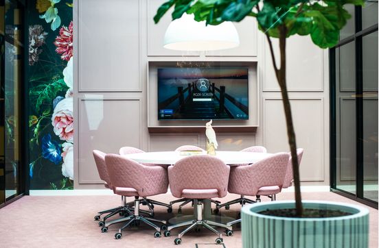 Vergaderruimte met roze stoelen en een grote plant